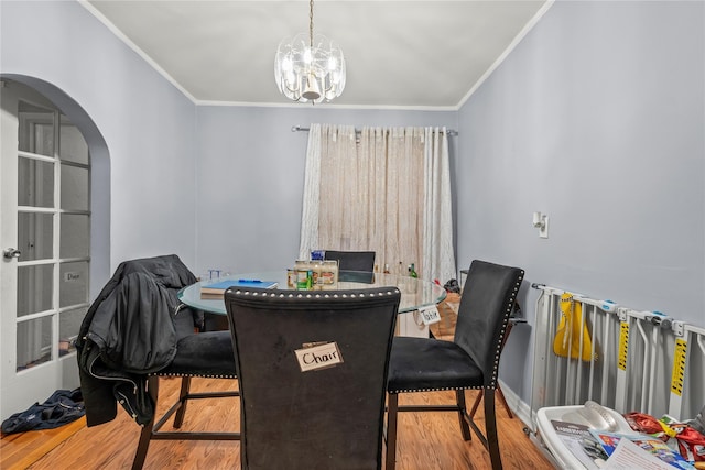 dining area featuring arched walkways, crown molding, wood finished floors, and a notable chandelier