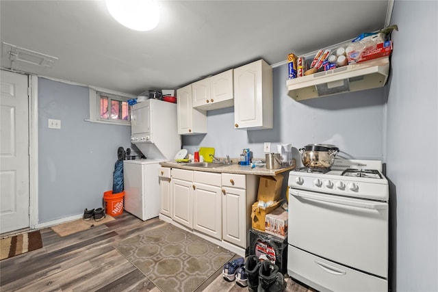 kitchen with white range with gas cooktop, white cabinets, stacked washer / dryer, wood finished floors, and light countertops