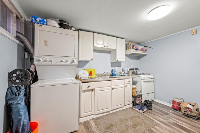 laundry room featuring stacked washer and dryer, laundry area, baseboards, light wood-style flooring, and a sink