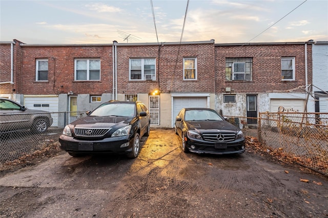 view of front facade featuring a garage, brick siding, and fence