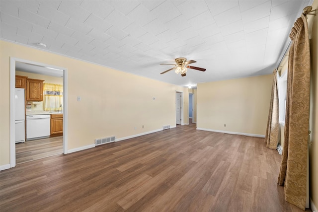 unfurnished living room featuring ceiling fan, visible vents, baseboards, and wood finished floors