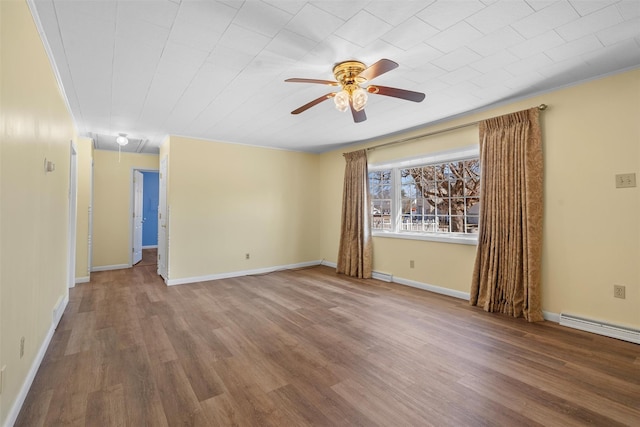 unfurnished room with ceiling fan, baseboards, attic access, wood finished floors, and a baseboard radiator