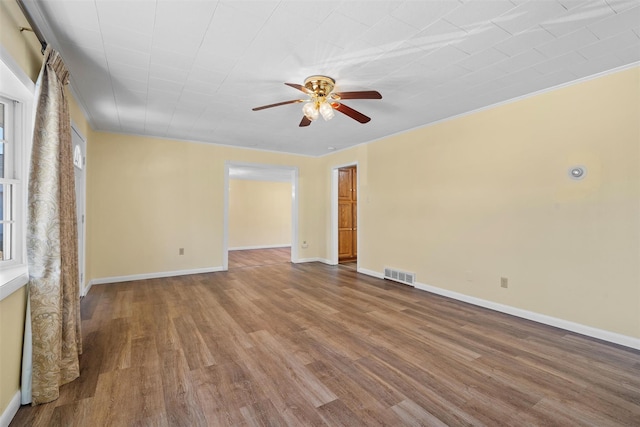 spare room featuring ceiling fan, visible vents, baseboards, and wood finished floors