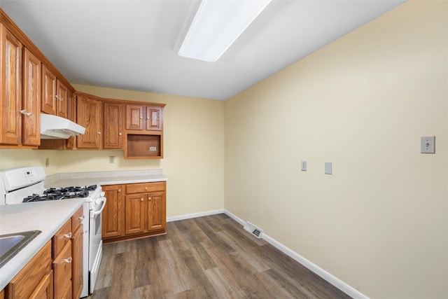 kitchen with baseboards, white gas stove, dark wood finished floors, under cabinet range hood, and light countertops