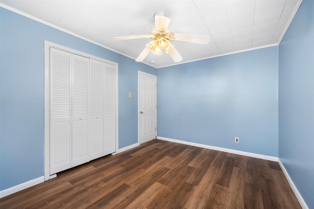 unfurnished bedroom featuring crown molding, baseboards, dark wood-style flooring, and a closet