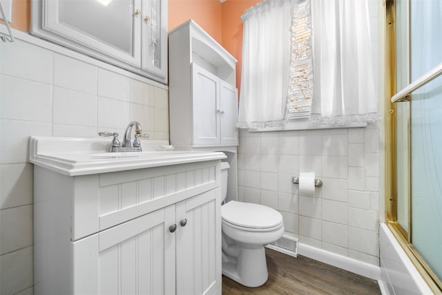 bathroom featuring visible vents, toilet, wood finished floors, tile walls, and vanity