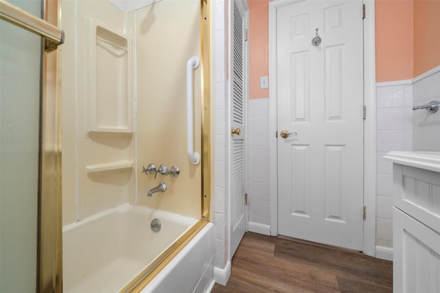 full bath featuring shower / tub combination, tile walls, wood finished floors, and wainscoting