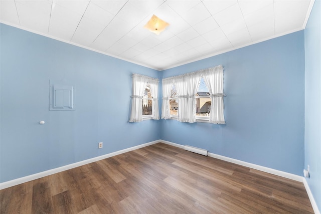 unfurnished room featuring baseboard heating, ornamental molding, baseboards, and wood finished floors