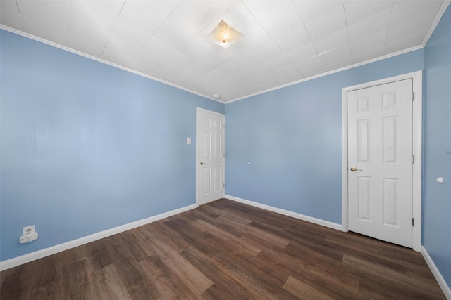 unfurnished room featuring baseboards, dark wood finished floors, and ornamental molding