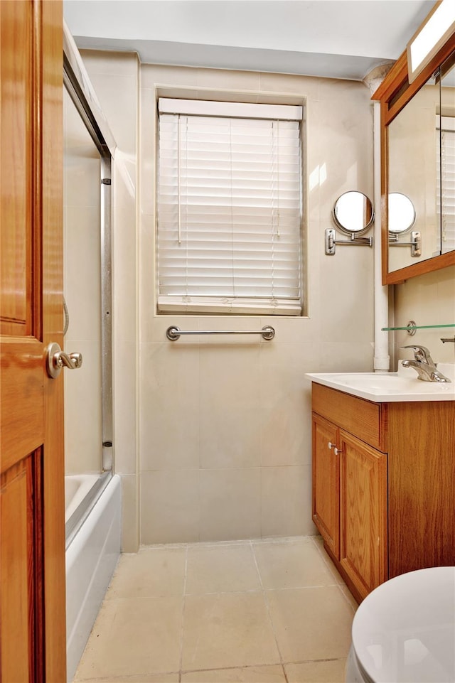 bathroom with tile walls, toilet, tub / shower combination, vanity, and tile patterned flooring