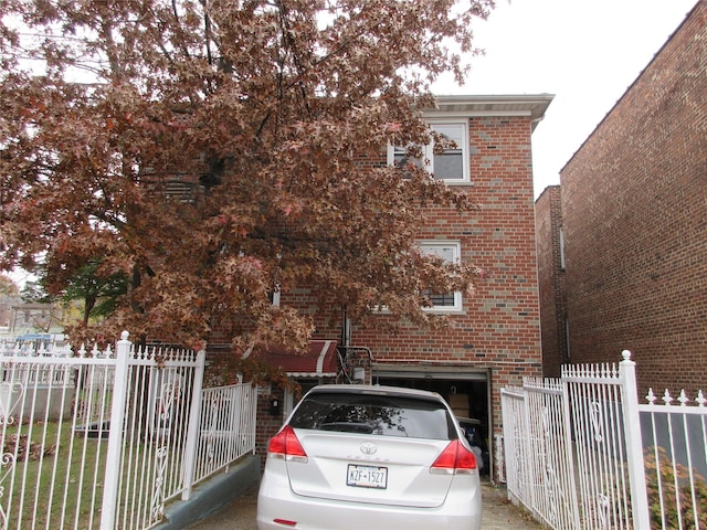 obstructed view of property with brick siding, an attached garage, and fence