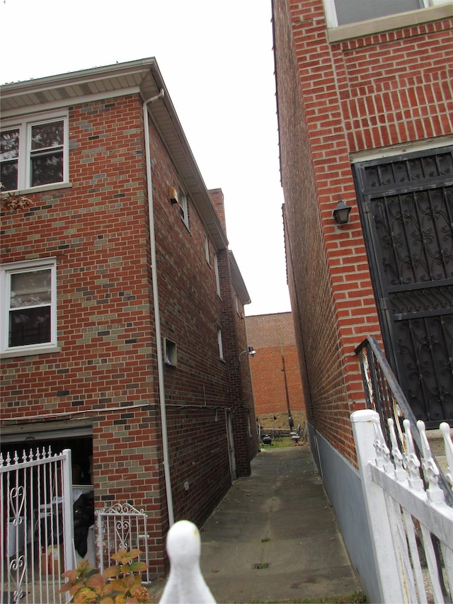 view of side of home with fence and brick siding