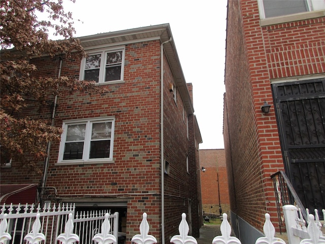 view of home's exterior featuring brick siding and fence