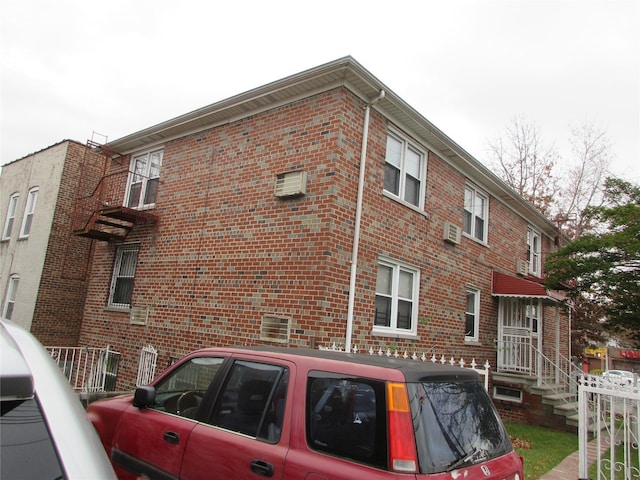 view of side of property featuring brick siding and fence