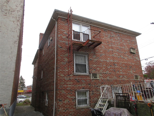 view of side of home with brick siding and a balcony