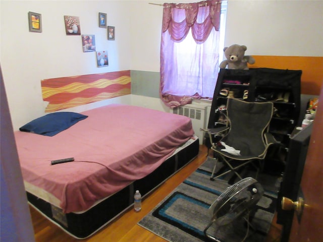 bedroom featuring radiator and wood finished floors