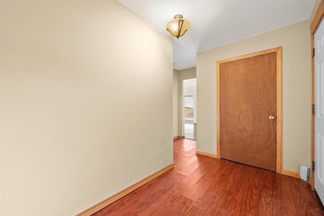 hall with baseboards and wood finished floors