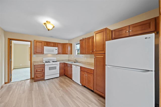 kitchen with light countertops, white appliances, brown cabinetry, and a sink