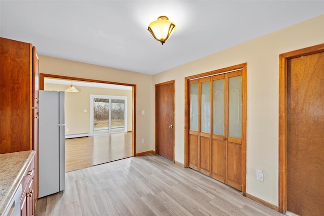 kitchen featuring a baseboard radiator, light wood-style flooring, freestanding refrigerator, dishwasher, and baseboards