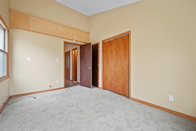 unfurnished bedroom with carpet floors, a closet, multiple windows, and baseboards