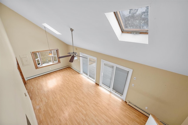 spare room featuring a skylight, a baseboard radiator, ceiling fan, wood finished floors, and high vaulted ceiling