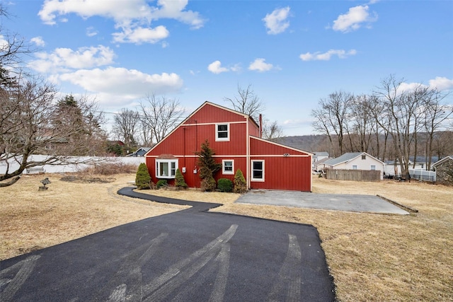 view of front facade with an outbuilding, fence, and a barn