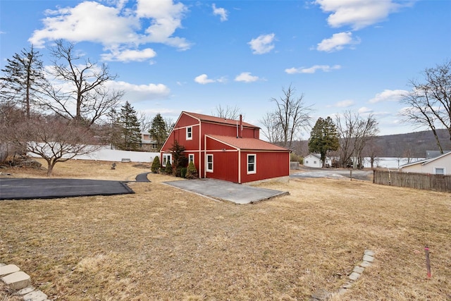 rear view of house featuring a yard, fence, and a patio