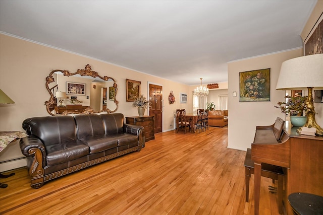 living area featuring a chandelier, light wood-type flooring, and crown molding