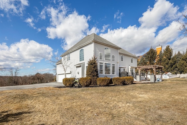 view of side of property featuring a garage, a yard, driveway, and a pergola