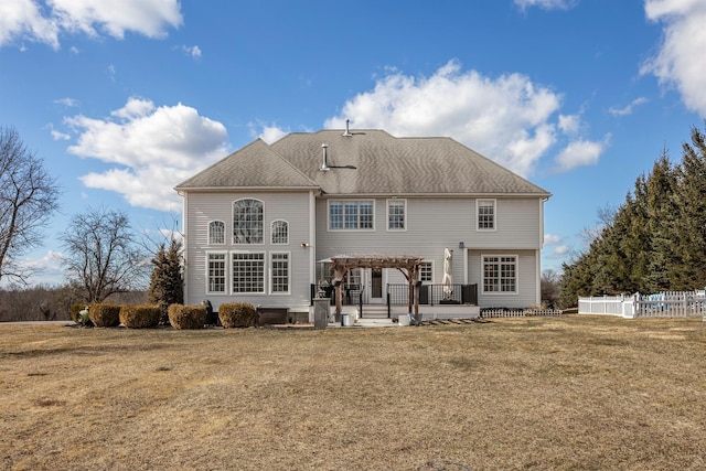 rear view of house with a pergola, roof with shingles, a yard, and fence