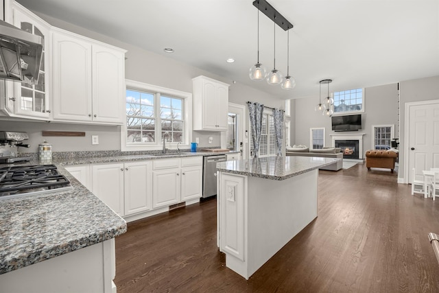 kitchen featuring dark wood-type flooring, a sink, a glass covered fireplace, white cabinetry, and appliances with stainless steel finishes