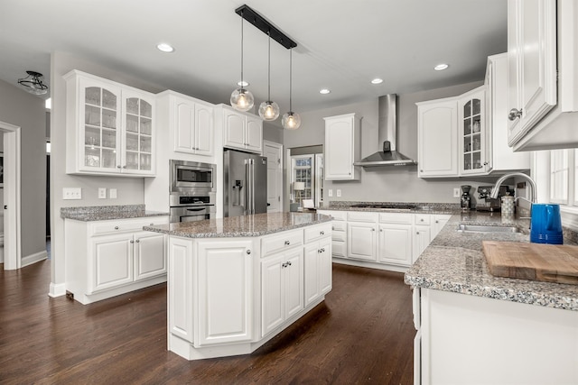 kitchen featuring a sink, dark wood finished floors, white cabinetry, stainless steel appliances, and wall chimney range hood