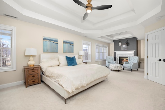 bedroom featuring carpet, visible vents, baseboards, a fireplace, and a raised ceiling