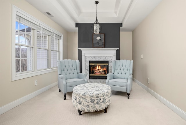 sitting room with visible vents, a fireplace, a raised ceiling, and baseboards