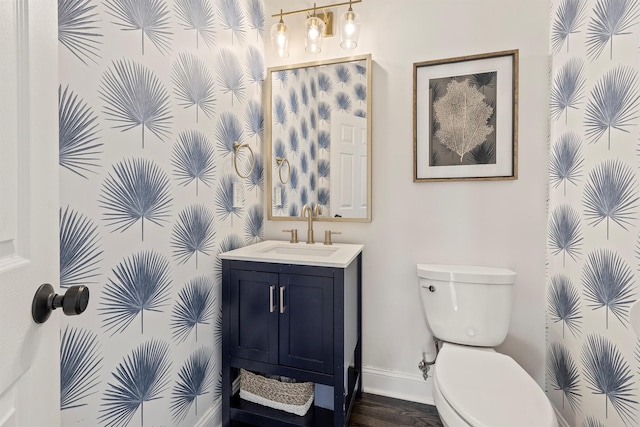 bathroom featuring baseboards, toilet, wood finished floors, and vanity