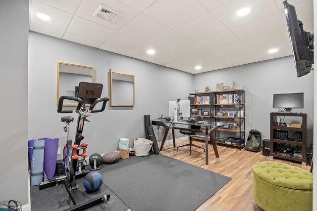 exercise room featuring visible vents, baseboards, recessed lighting, wood finished floors, and a paneled ceiling