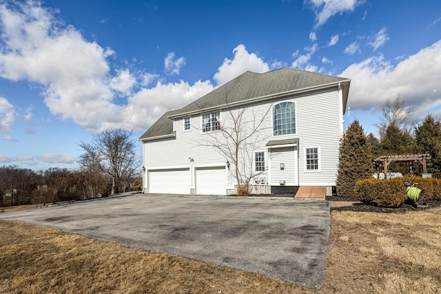 view of front of property with a garage, driveway, and roof with shingles