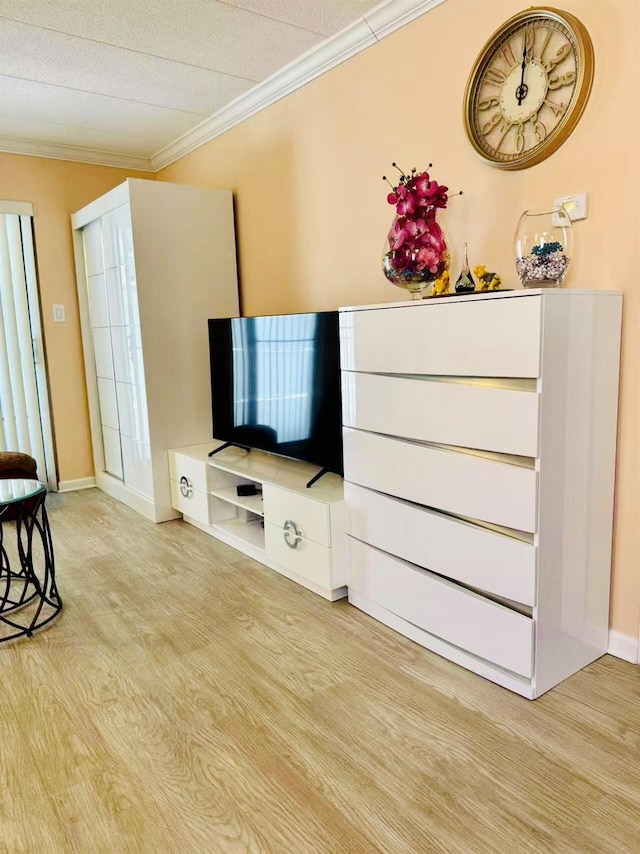 living area featuring light wood-style floors, baseboards, and crown molding