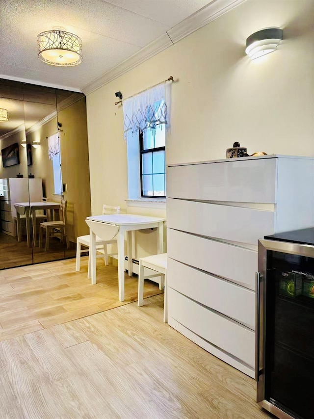 dining room featuring wine cooler, ornamental molding, and wood finished floors