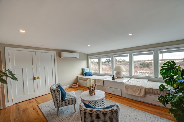 living area featuring a wall unit AC, recessed lighting, light wood-style floors, and baseboards