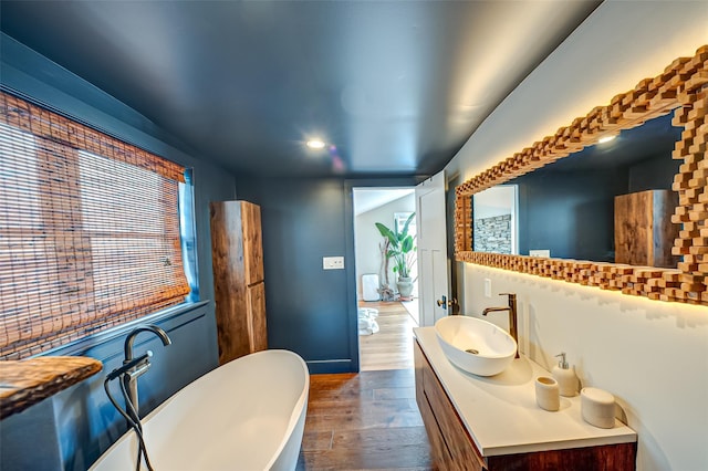 bathroom with baseboards, a freestanding bath, wood finished floors, and vanity