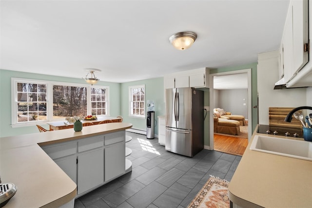 kitchen with white cabinets, a baseboard radiator, freestanding refrigerator, light countertops, and a sink