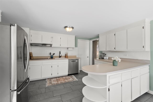 kitchen with under cabinet range hood, a peninsula, appliances with stainless steel finishes, decorative backsplash, and open shelves