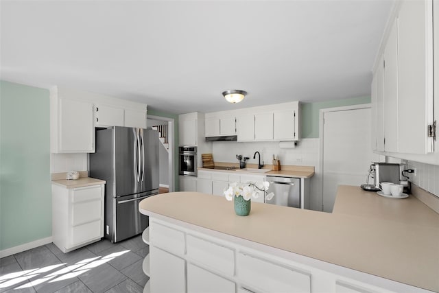 kitchen featuring white cabinets, appliances with stainless steel finishes, a peninsula, tile patterned flooring, and light countertops