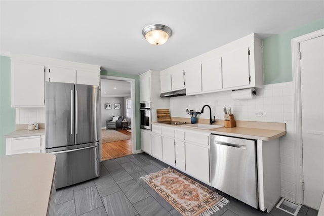 kitchen featuring light countertops, appliances with stainless steel finishes, white cabinetry, a sink, and under cabinet range hood