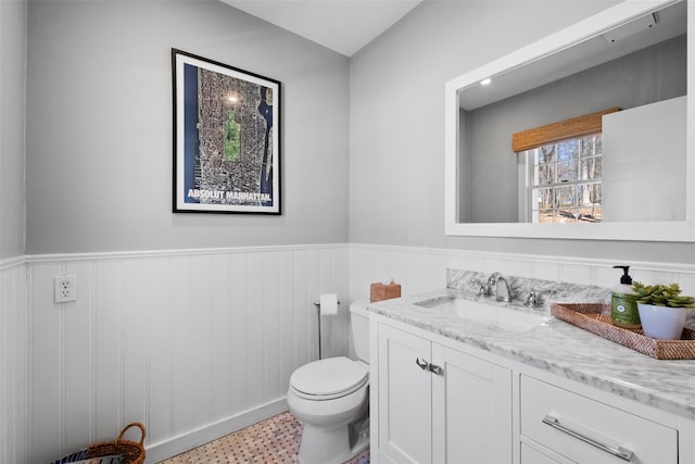 half bathroom featuring wainscoting, vanity, and toilet