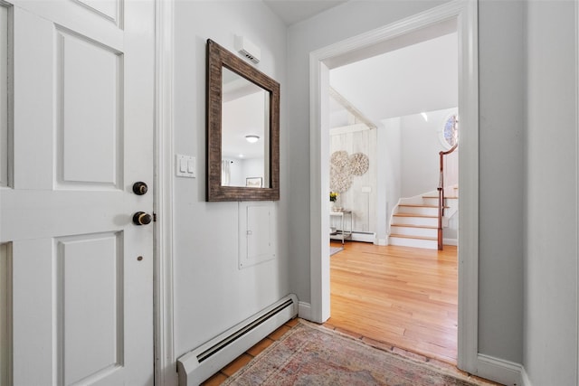 interior space with baseboards, stairway, baseboard heating, and wood finished floors