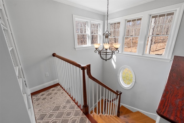 stairway featuring ornamental molding, a notable chandelier, baseboards, and wood finished floors