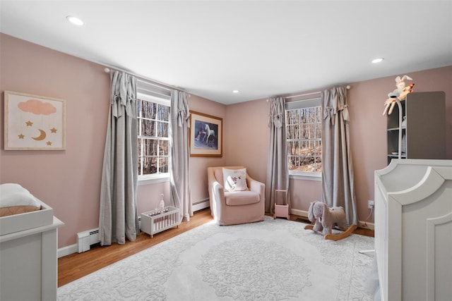 living area featuring a baseboard radiator, a healthy amount of sunlight, and wood finished floors