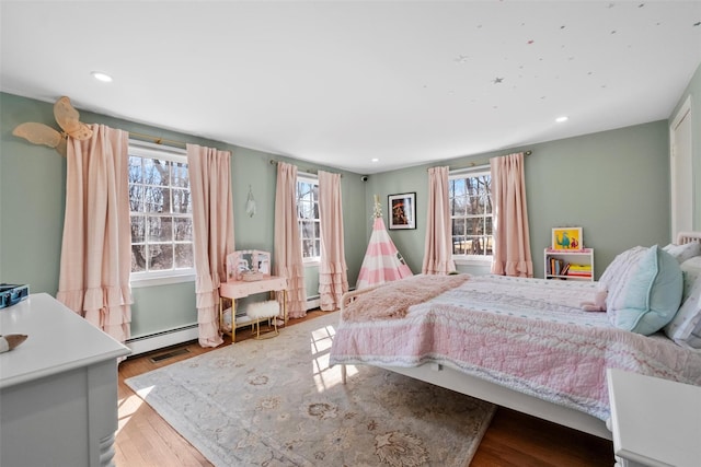 bedroom featuring light wood finished floors, baseboard heating, and recessed lighting